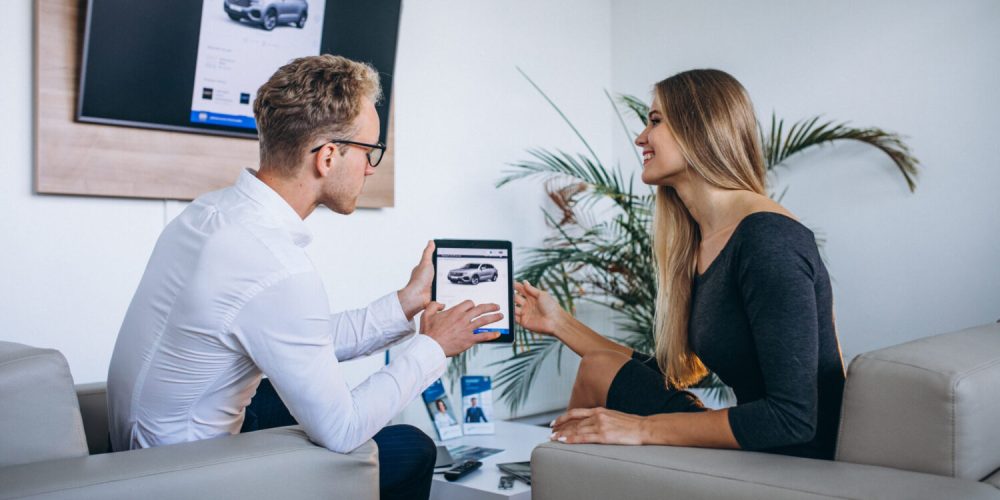 Man and woman in a car showroom using tablet